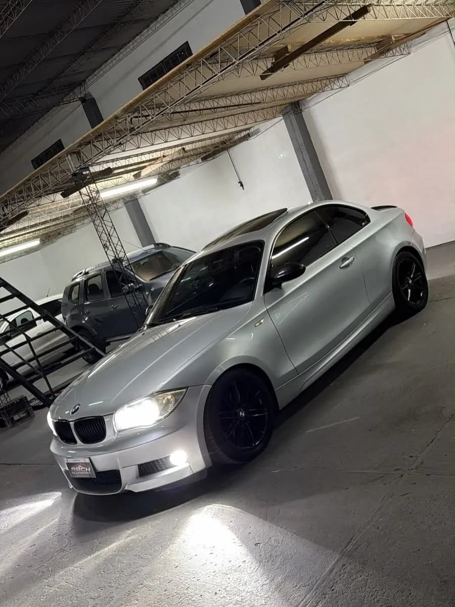 BMW 125i coupé gris plata con las luces encendidas, en el salón