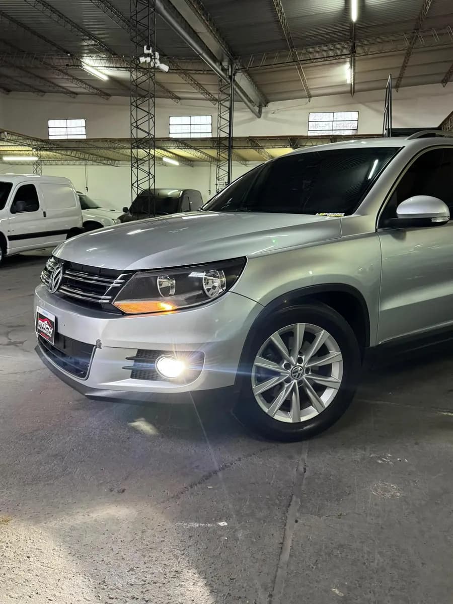 Frente de una Volkswagen Tiguan gris con las luces encendidas, en el salón